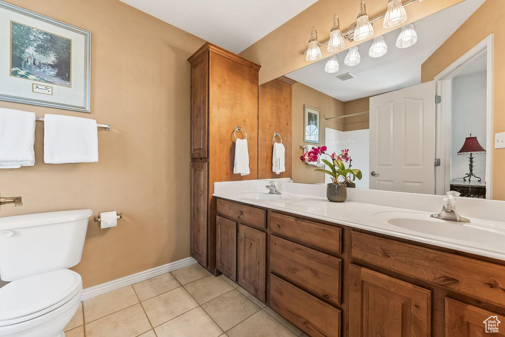 Bathroom featuring double vanity, tile flooring, and toilet