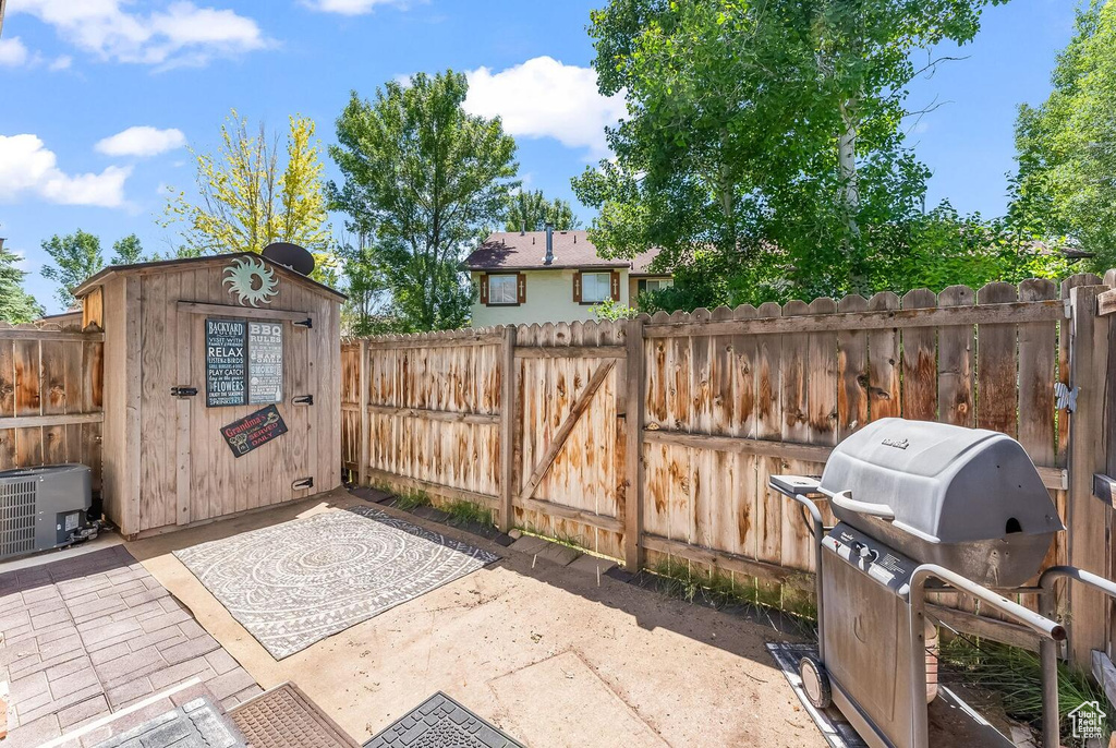 View of patio / terrace with central AC, a grill, and a shed