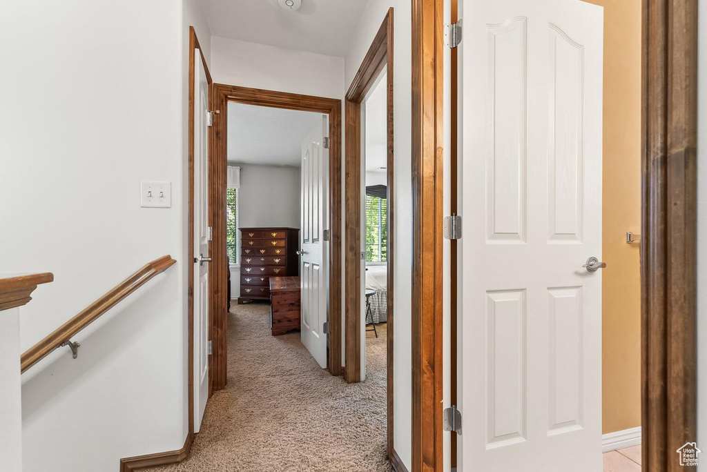 Corridor featuring light colored carpet