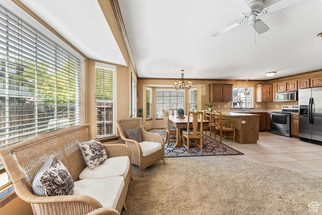 Tiled living room with sink, crown molding, and ceiling fan with notable chandelier