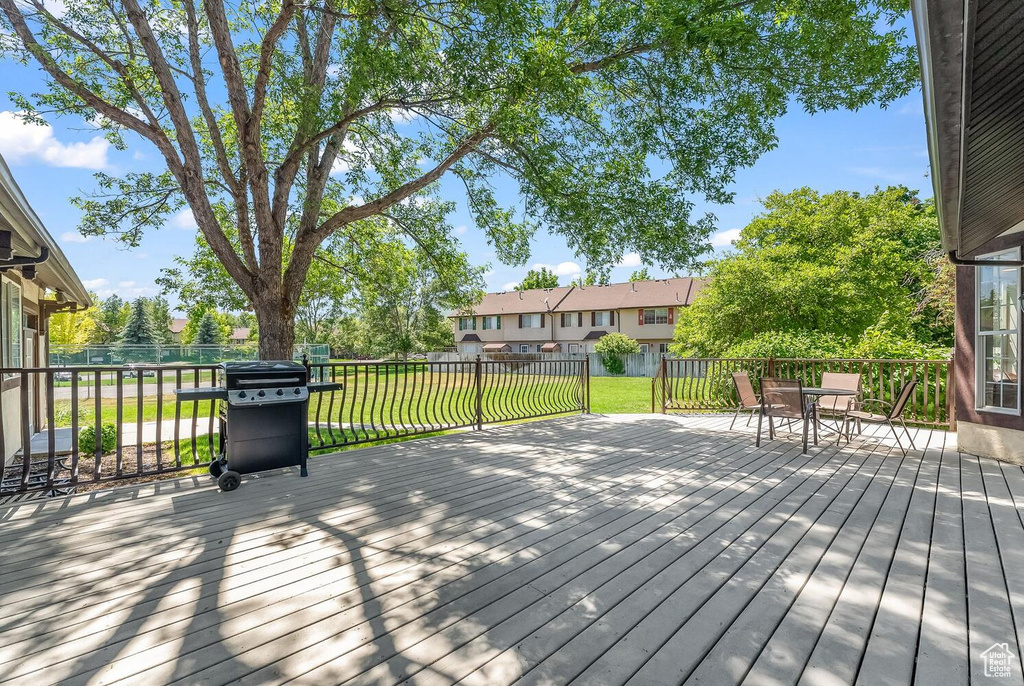 Wooden terrace featuring a lawn and area for grilling