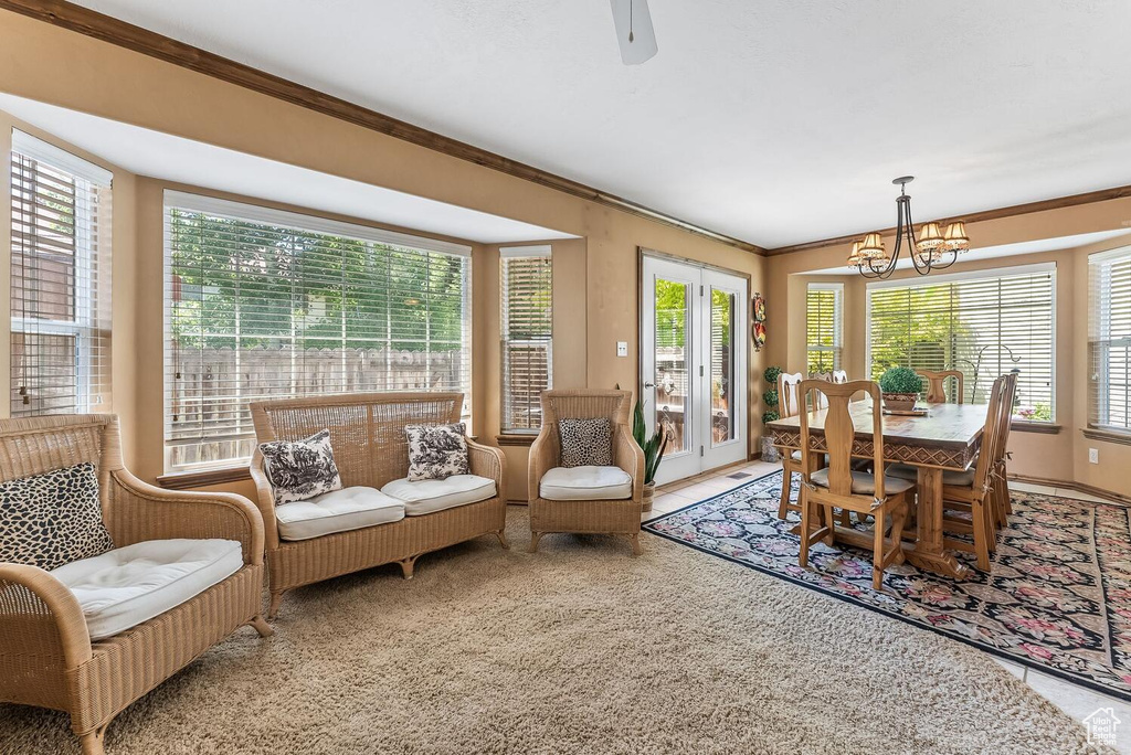 Carpeted dining area featuring ornamental molding and ceiling fan with notable chandelier