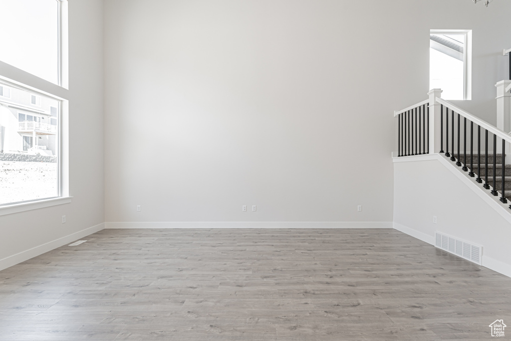 Empty room with light wood-type flooring and a towering ceiling