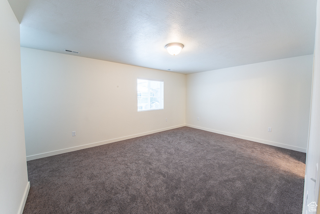 Spare room featuring dark colored carpet