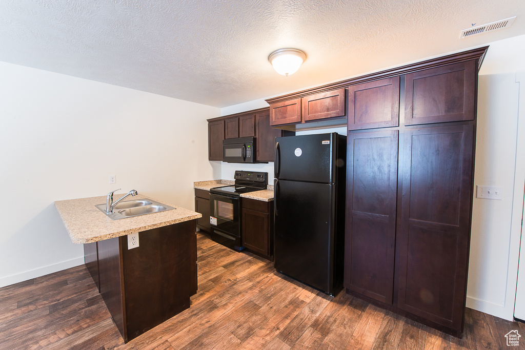 Kitchen with black appliances, sink, dark hardwood / wood-style floors, and a textured ceiling