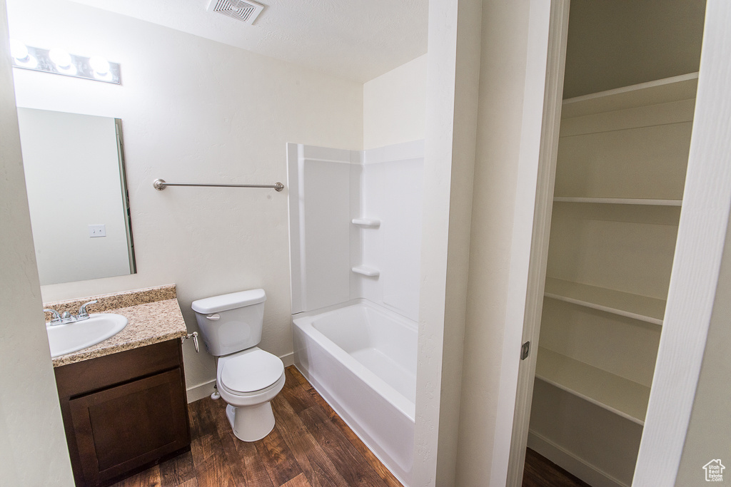 Full bathroom featuring washtub / shower combination, vanity, toilet, and hardwood / wood-style floors