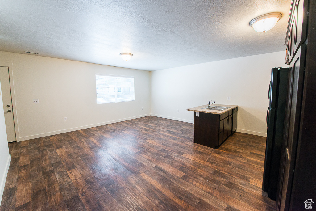 Unfurnished room featuring sink, a textured ceiling, and dark hardwood / wood-style floors