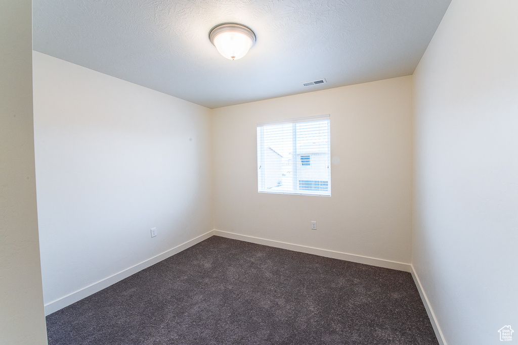 Spare room featuring dark colored carpet