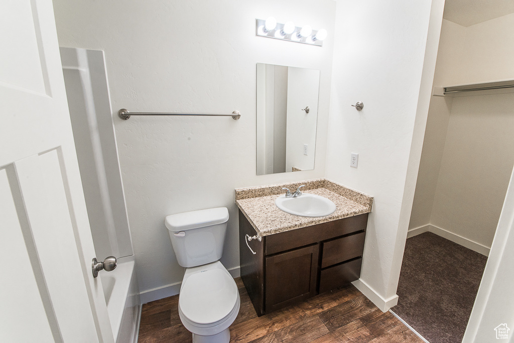 Full bathroom with vanity with extensive cabinet space, toilet, hardwood / wood-style flooring, and tub / shower combination