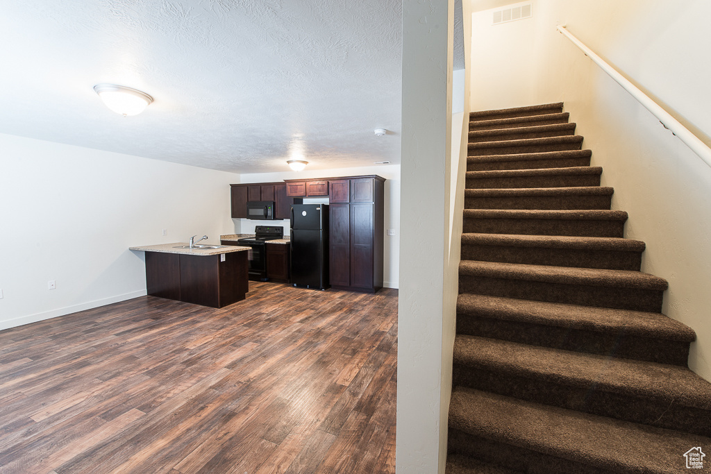 Stairway with sink and dark wood-type flooring