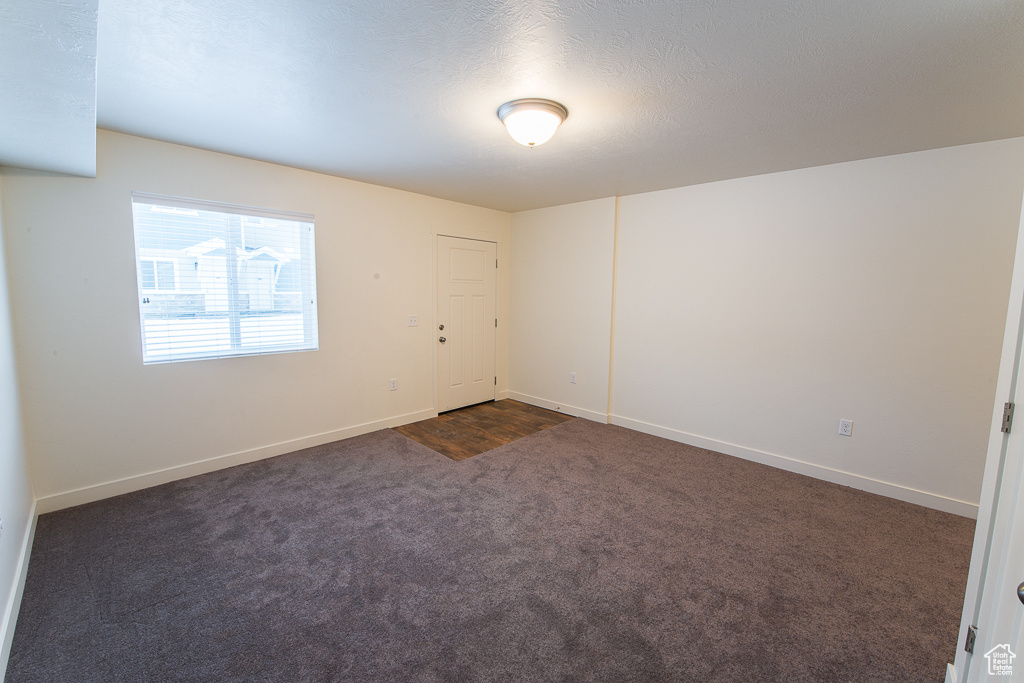 Unfurnished room featuring dark colored carpet