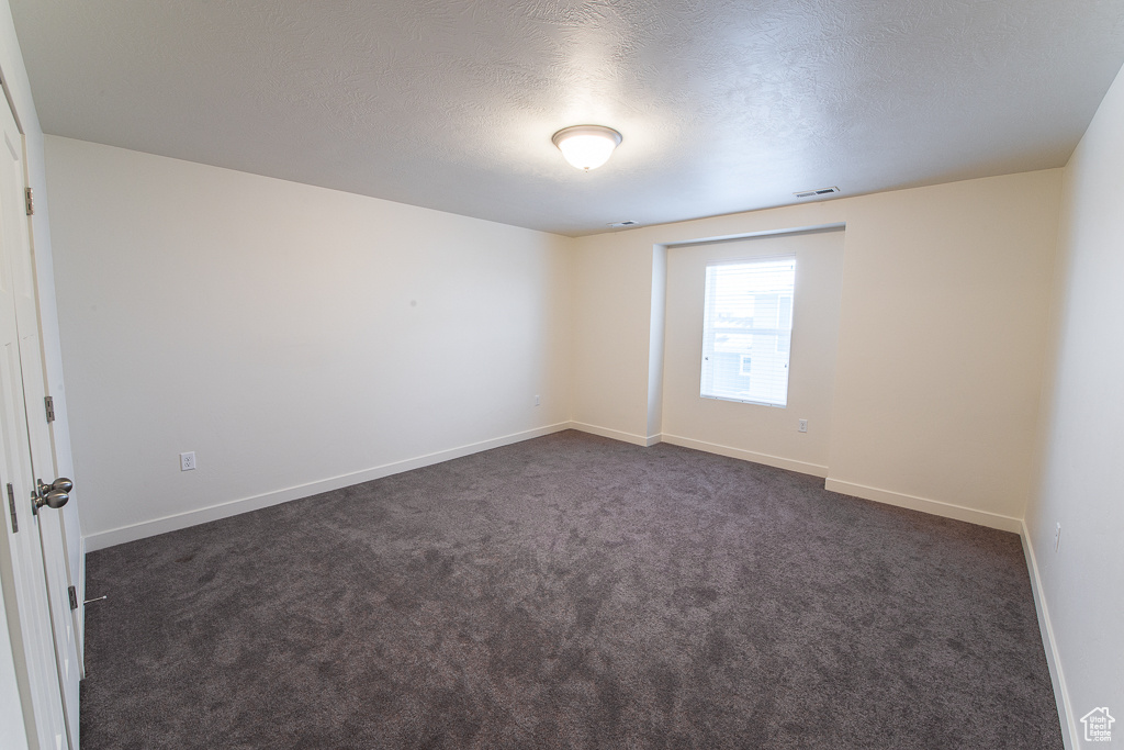 Carpeted spare room with a textured ceiling