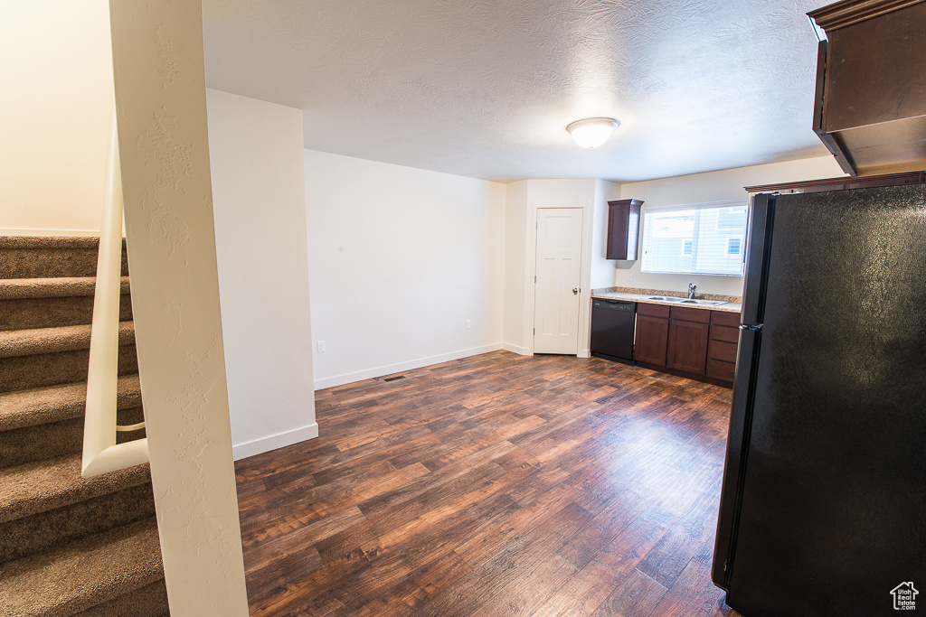 Kitchen featuring a textured ceiling, black appliances, dark hardwood / wood-style floors, dark brown cabinets, and sink