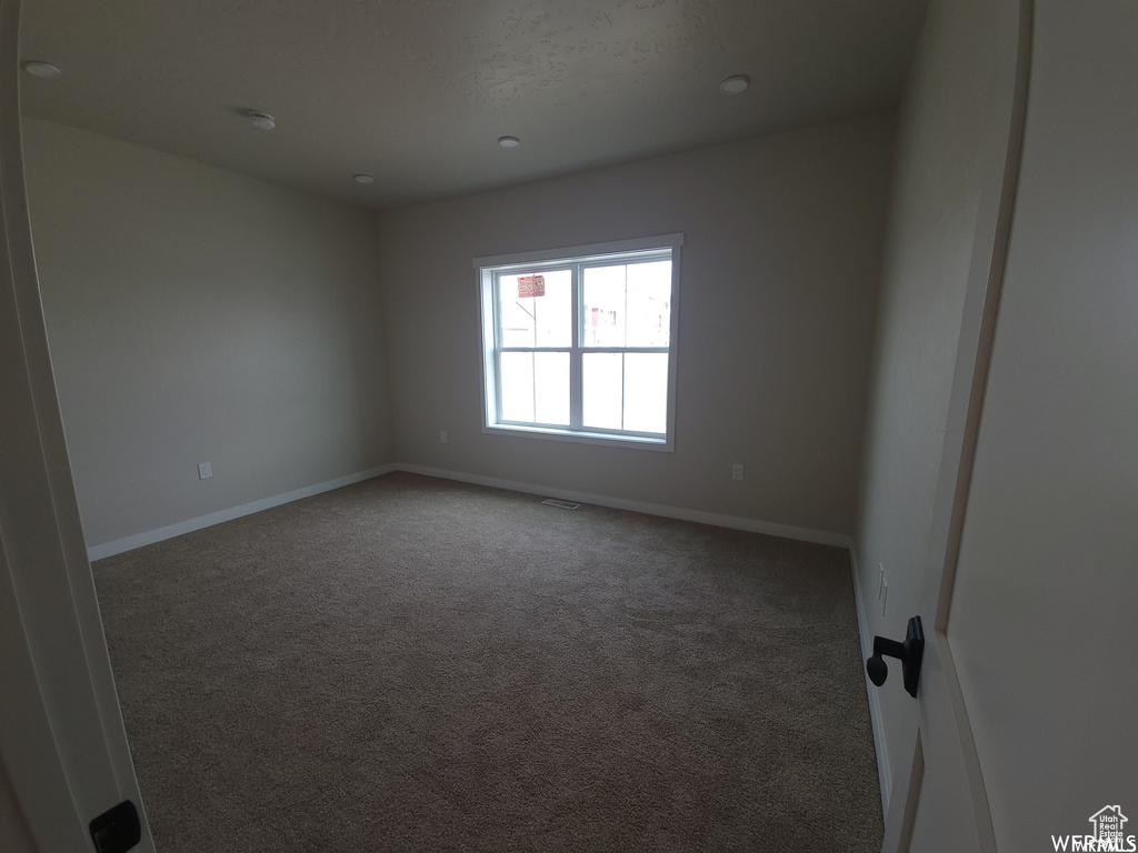 Spare room featuring dark colored carpet