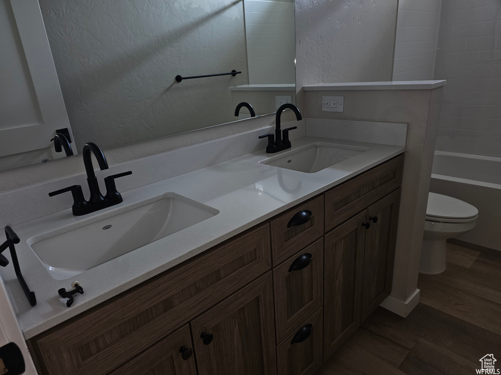 Bathroom with wood-type flooring, double vanity, and toilet