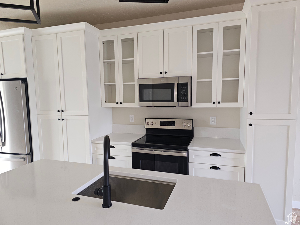 Kitchen featuring appliances with stainless steel finishes, white cabinetry, and sink