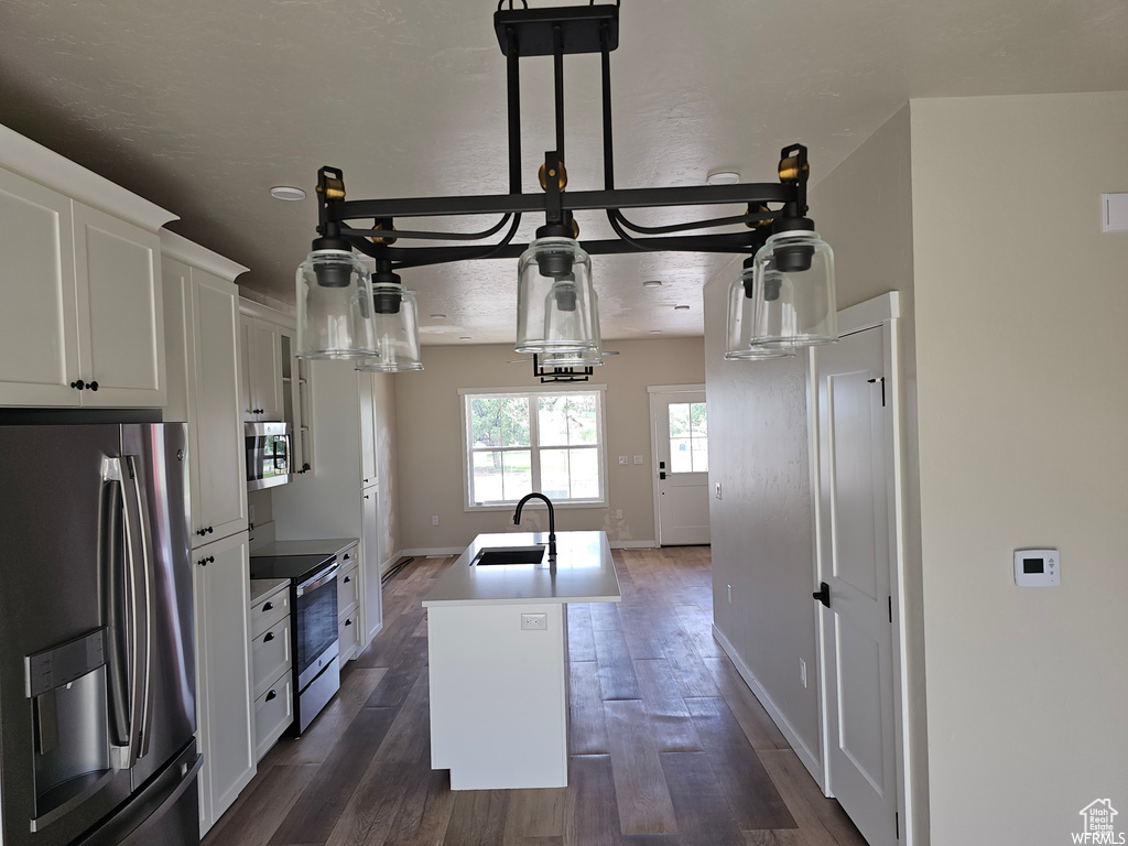 Kitchen with stainless steel appliances, a center island with sink, sink, and dark wood-type flooring