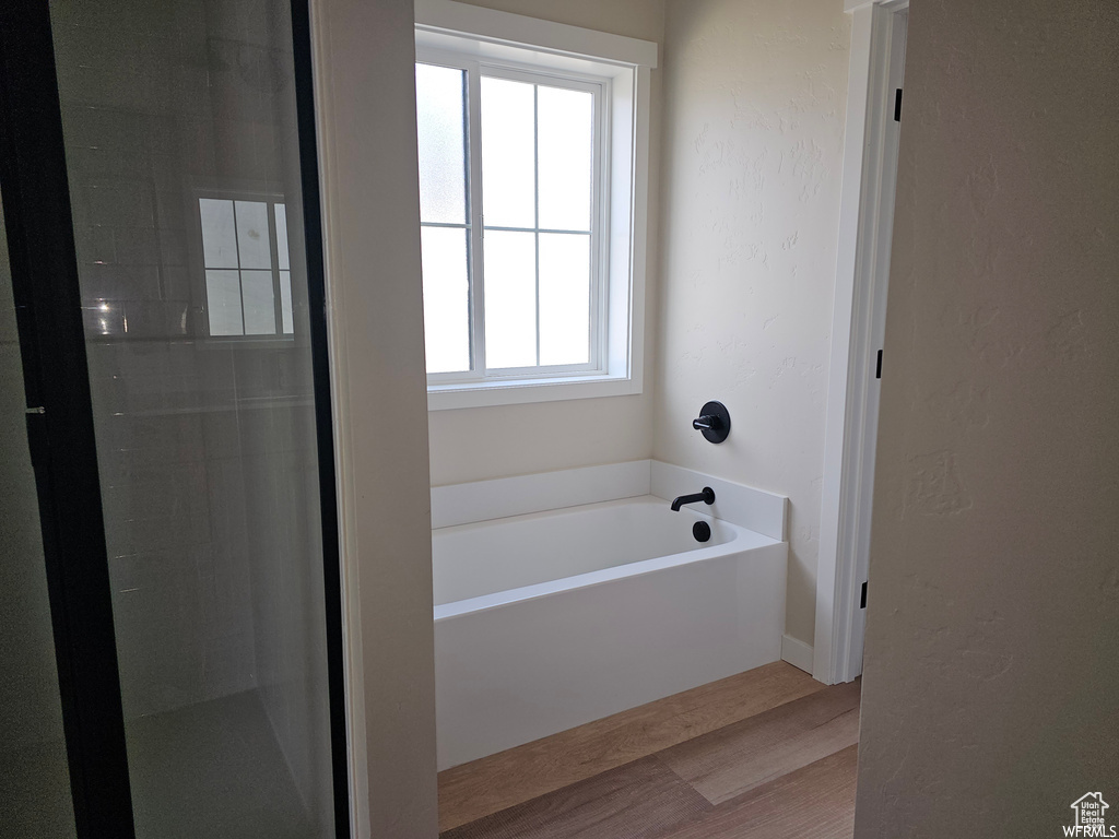 Bathroom featuring a healthy amount of sunlight, hardwood / wood-style flooring, and a washtub