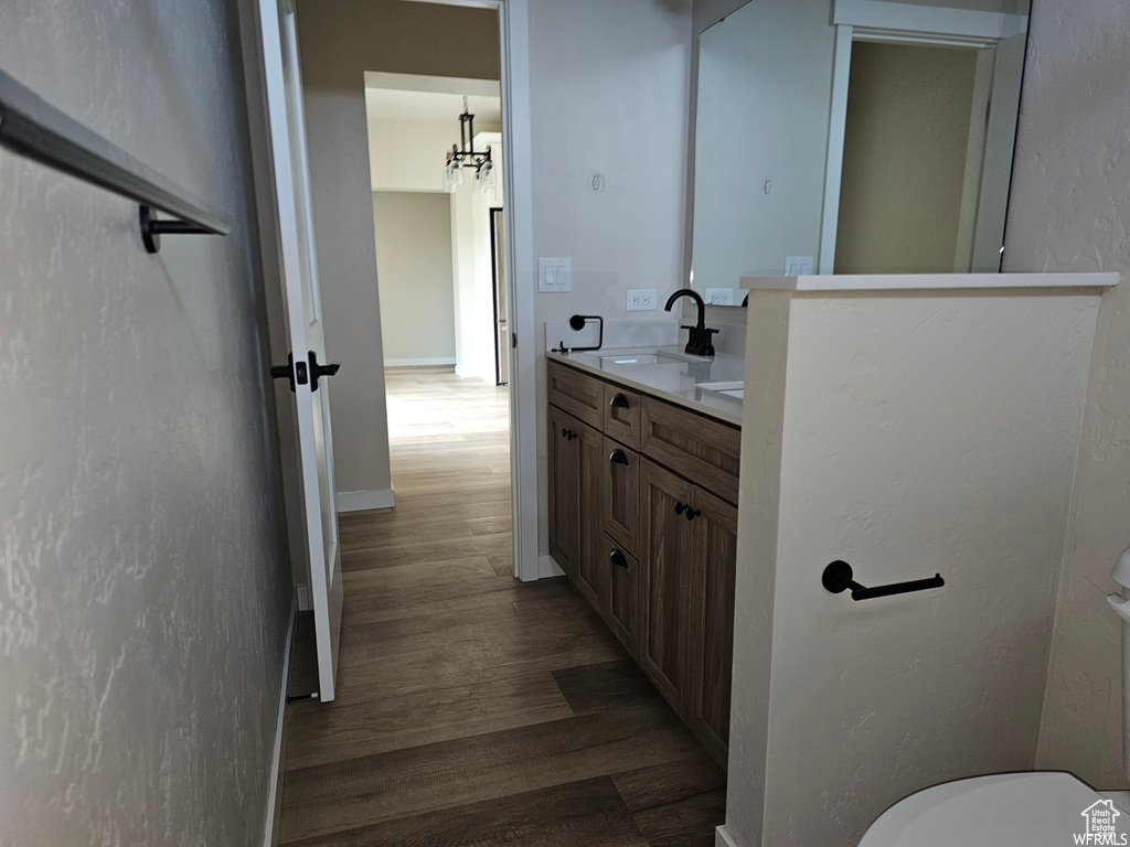 Bathroom featuring an inviting chandelier, vanity, toilet, and wood-type flooring