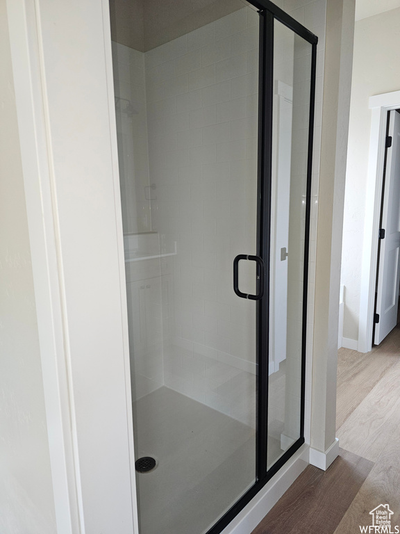 Bathroom featuring a shower with shower door and hardwood / wood-style floors