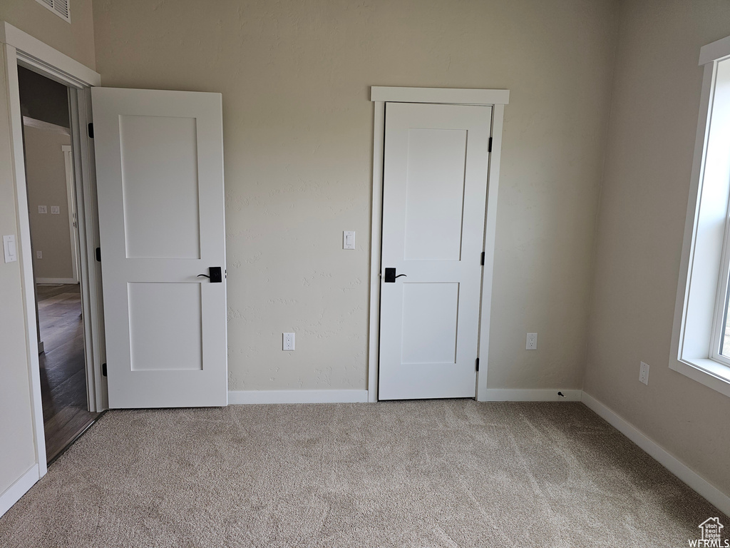 Unfurnished bedroom with light colored carpet