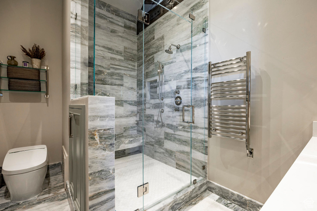 Full bath with radiator heating unit, a towel warming rack, and a shower stall