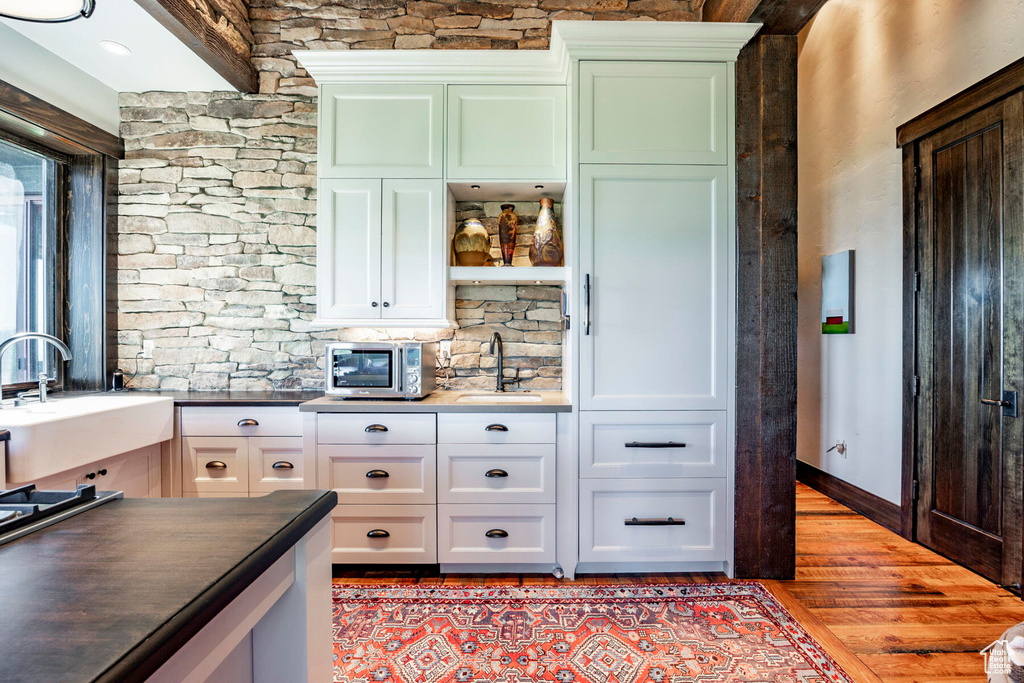 Kitchen featuring light wood finished floors, dark countertops, white cabinetry, decorative backsplash, and open shelves