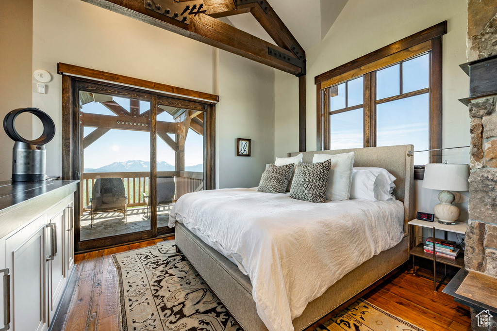 Bedroom featuring access to exterior, wood-type flooring, and high vaulted ceiling