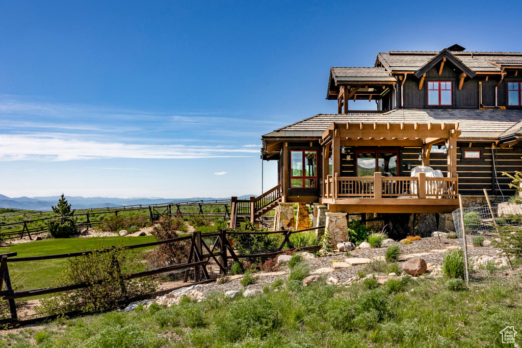 View of front of property featuring a pergola, a deck with mountain view, stairs, and a rural view