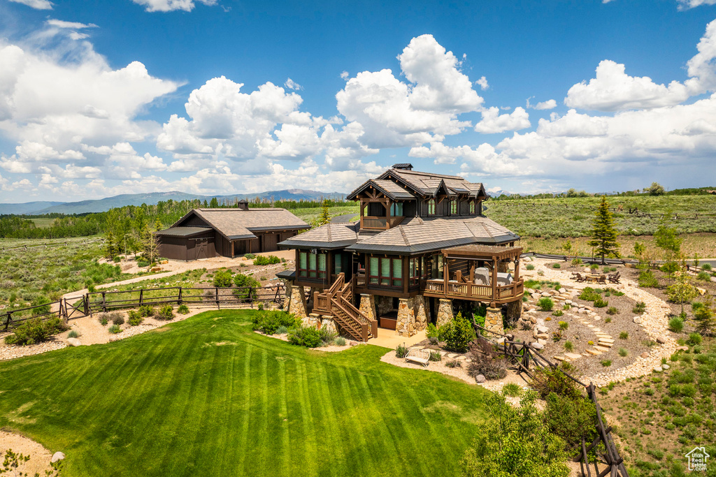 Back of property featuring a sunroom, stairway, a deck with mountain view, and a rural view