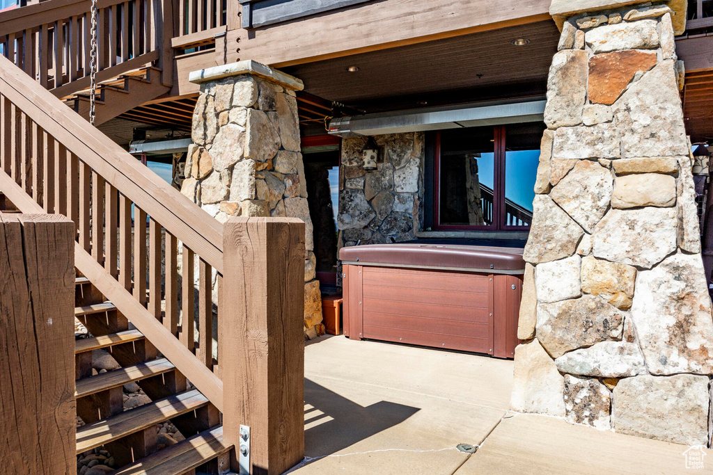 Entrance to property with stone siding and a hot tub