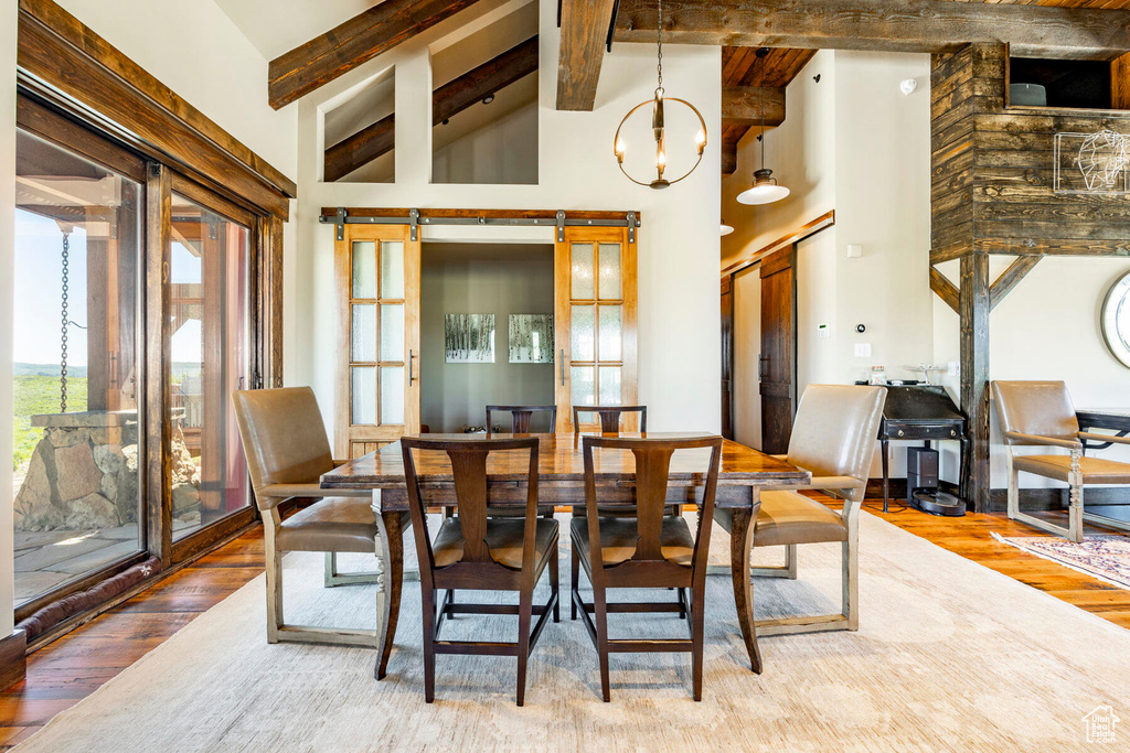 Dining area featuring wood-type flooring, beamed ceiling, high vaulted ceiling, and a chandelier