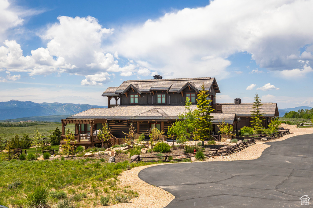 Log cabin featuring a mountain view, curved driveway, and a chimney