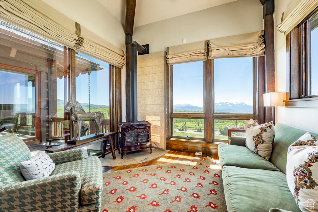 Living room featuring a wood stove, healthy amount of natural light, a mountain view, wood finished floors, and lofted ceiling