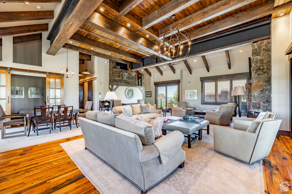 Living room featuring a chandelier, a wood ceiling with exposed beams, wood-type flooring, healthy amount of natural light, and a towering ceiling