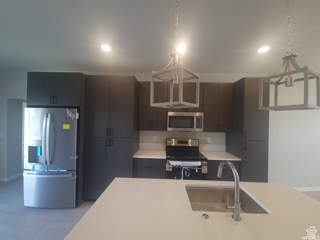 Kitchen with appliances with stainless steel finishes, decorative light fixtures, sink, and dark brown cabinets