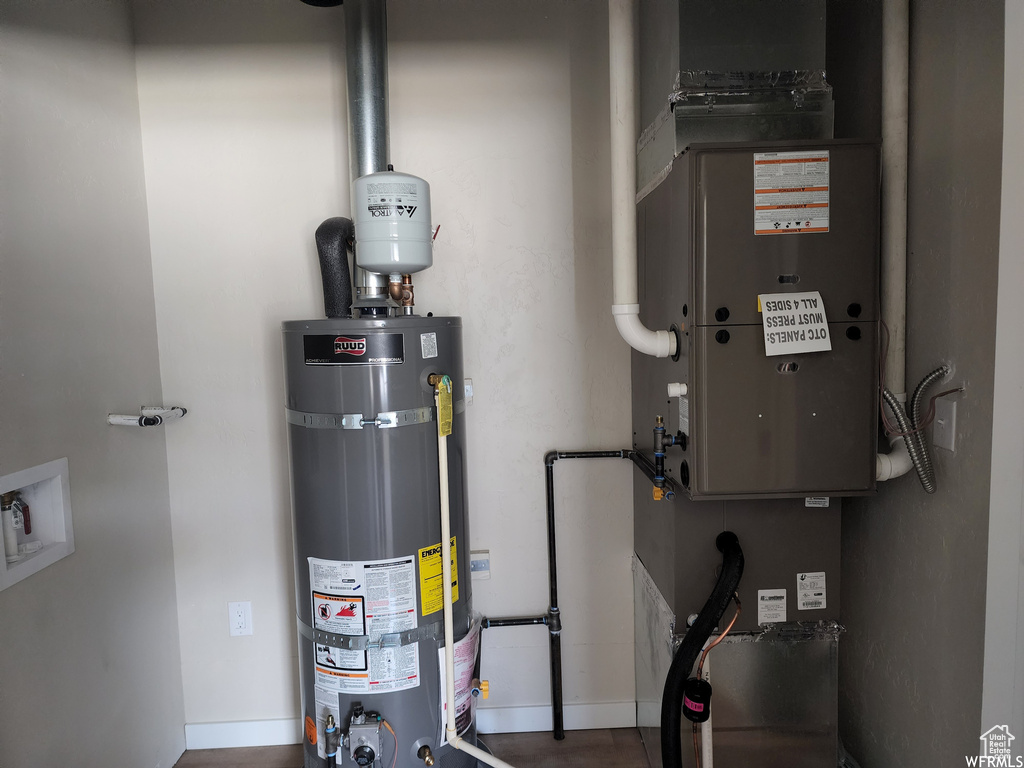 Utility room featuring strapped water heater