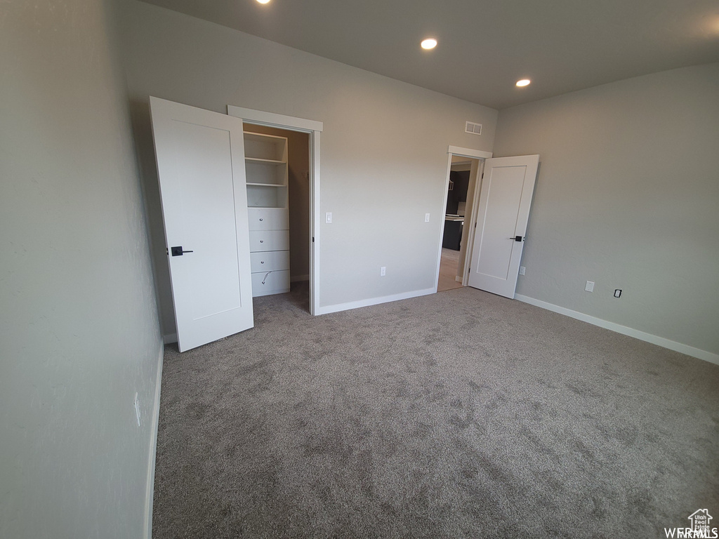 Unfurnished bedroom featuring carpet, a closet, and a walk in closet