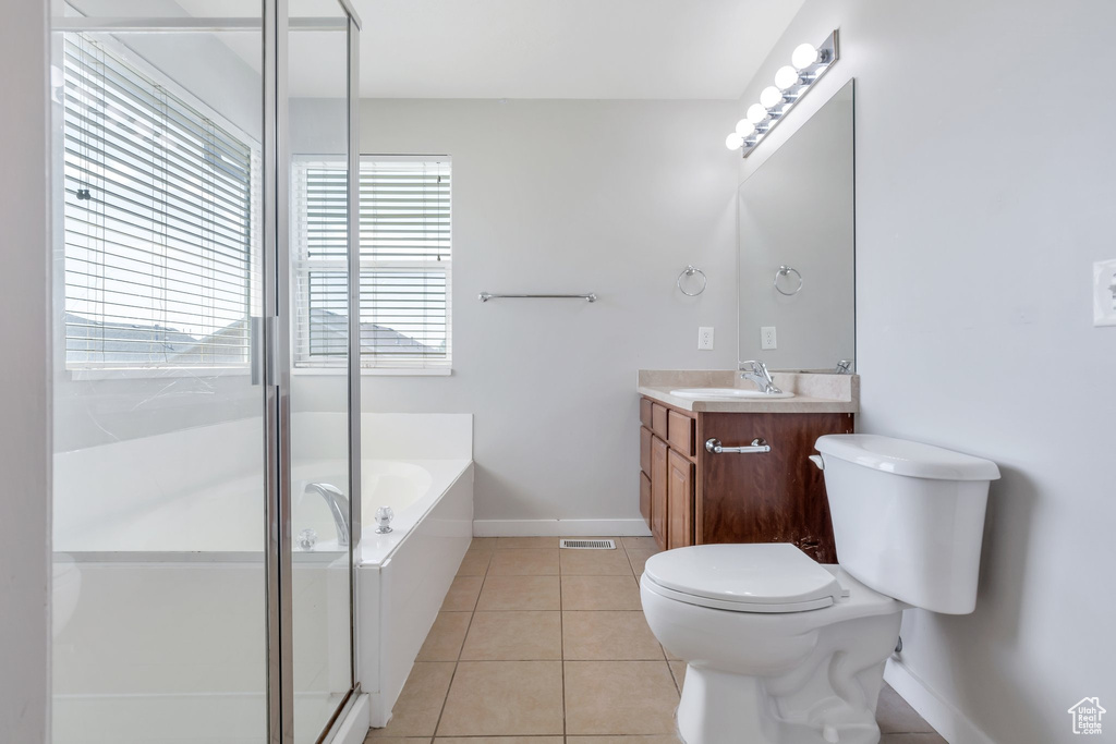 Bathroom with a bath to relax in, a healthy amount of sunlight, oversized vanity, toilet, and tile floors