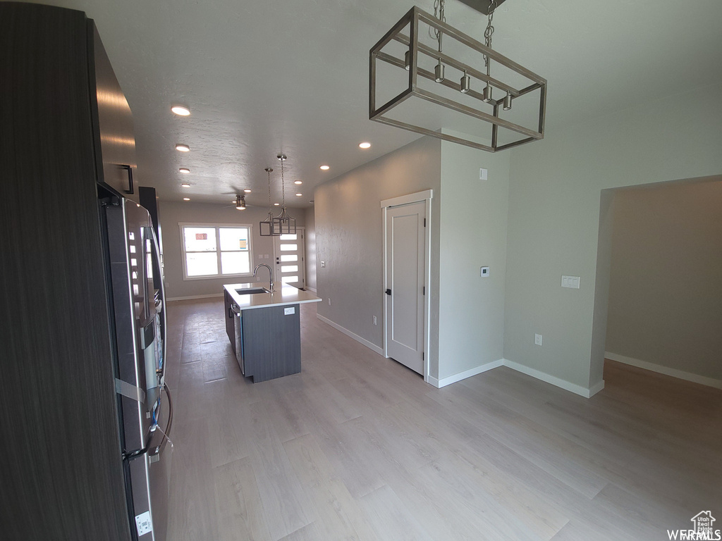 Kitchen with a center island with sink, sink, light wood-type flooring, and pendant lighting