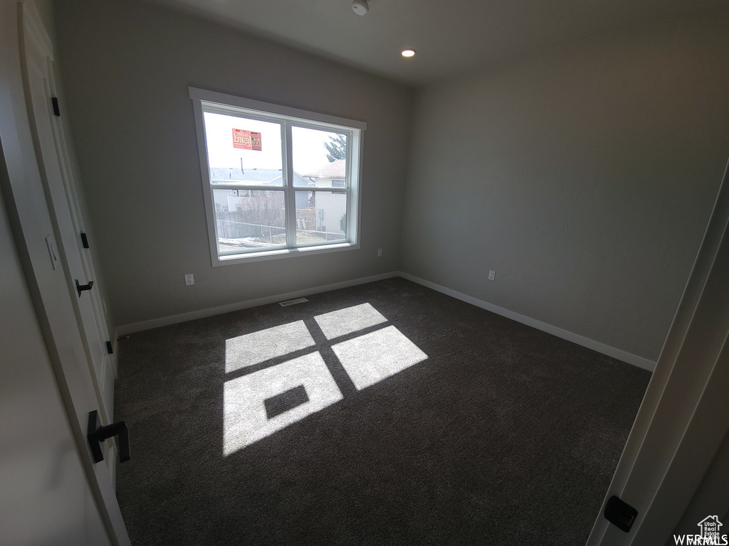 Spare room featuring dark colored carpet