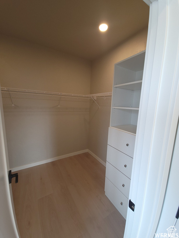 Walk in closet with hardwood / wood-style flooring