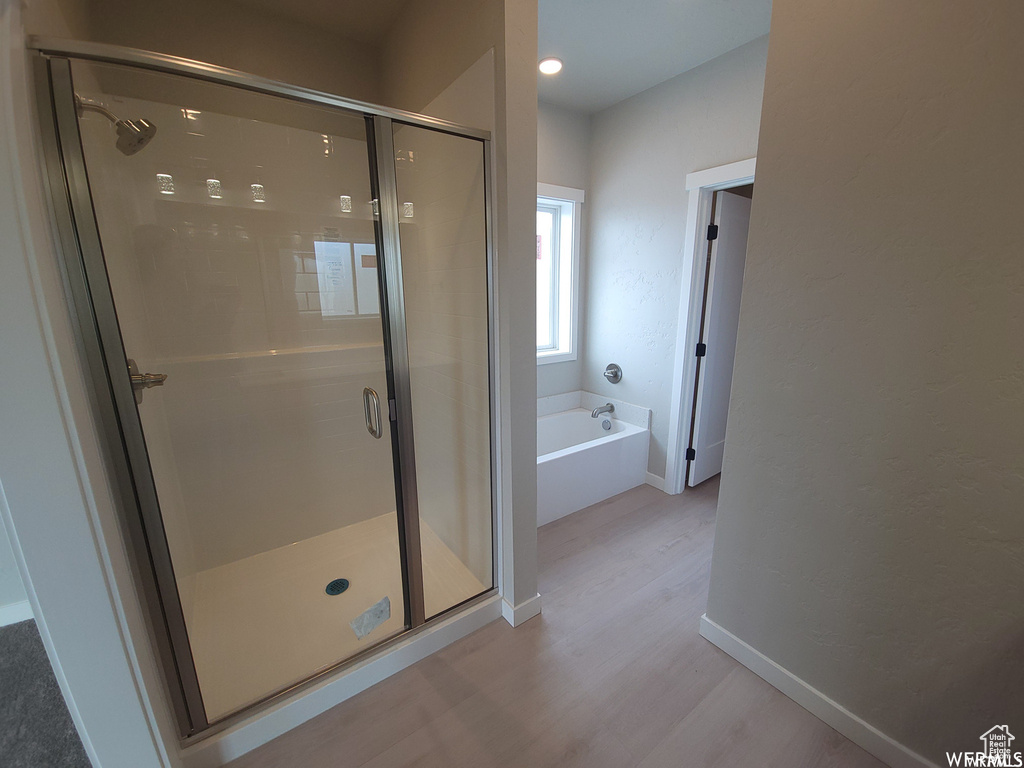 Bathroom with hardwood / wood-style floors and separate shower and tub