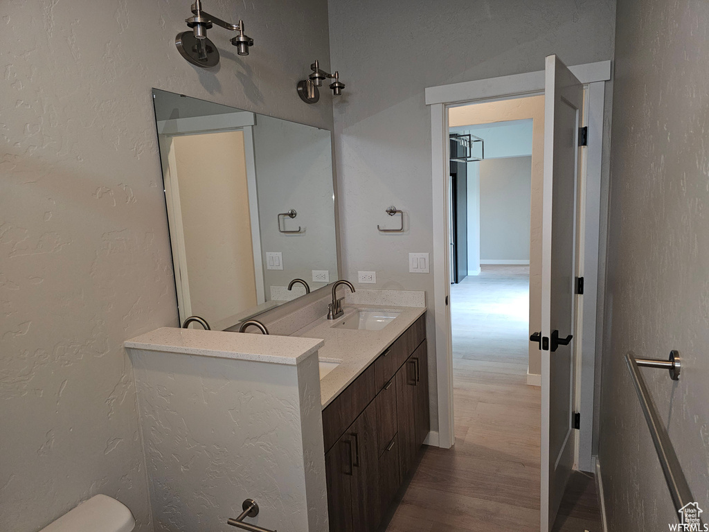 Bathroom with hardwood / wood-style floors, double vanity, and toilet