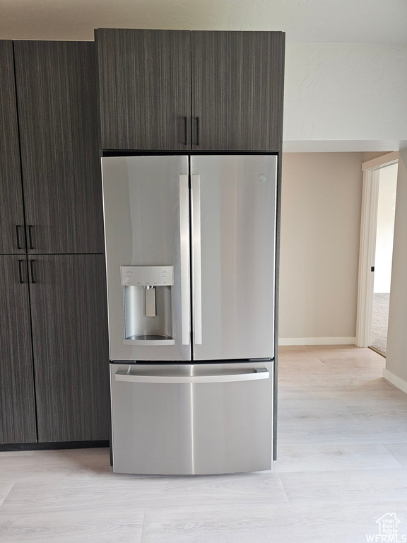 Kitchen with stainless steel fridge with ice dispenser, light wood-type flooring, and dark brown cabinetry