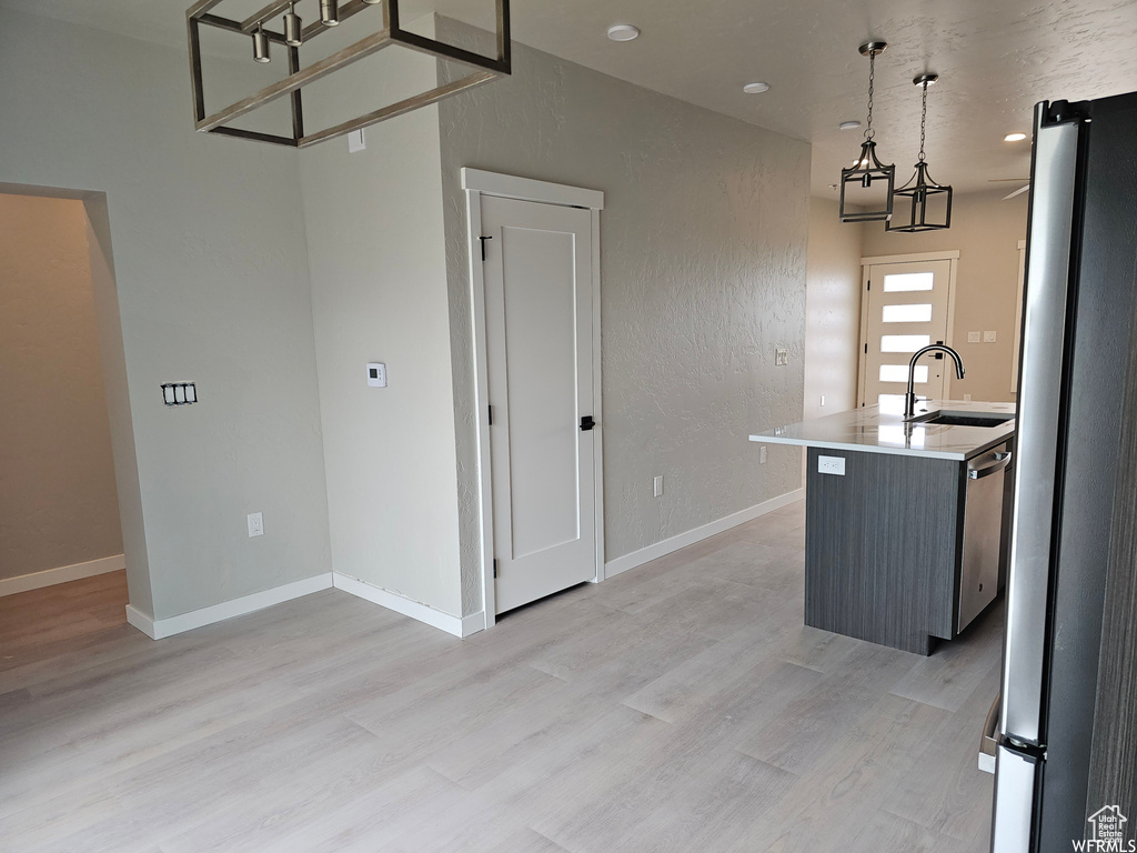 Kitchen with decorative light fixtures, light hardwood / wood-style floors, sink, and appliances with stainless steel finishes