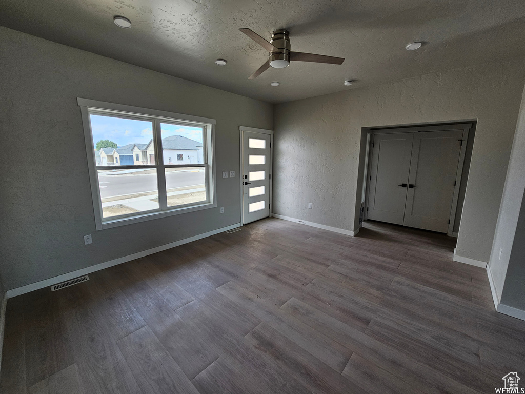 Empty room with ceiling fan and dark wood-type flooring