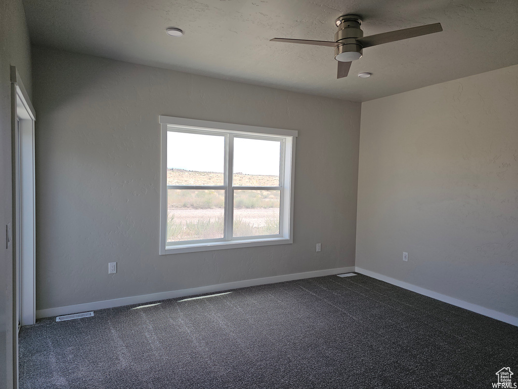 Carpeted spare room featuring ceiling fan