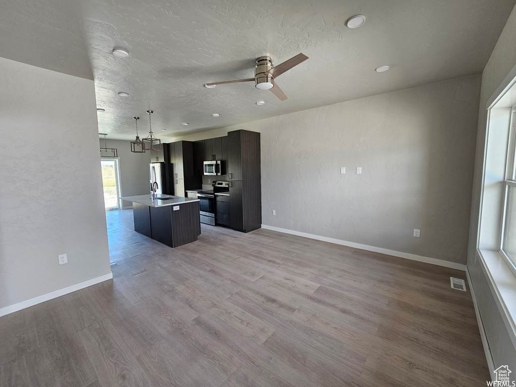 Unfurnished living room featuring sink, light wood-type flooring, and ceiling fan