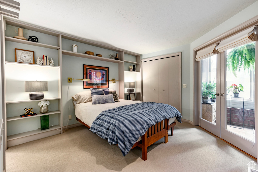 Carpeted bedroom featuring a closet, french doors, and access to outside